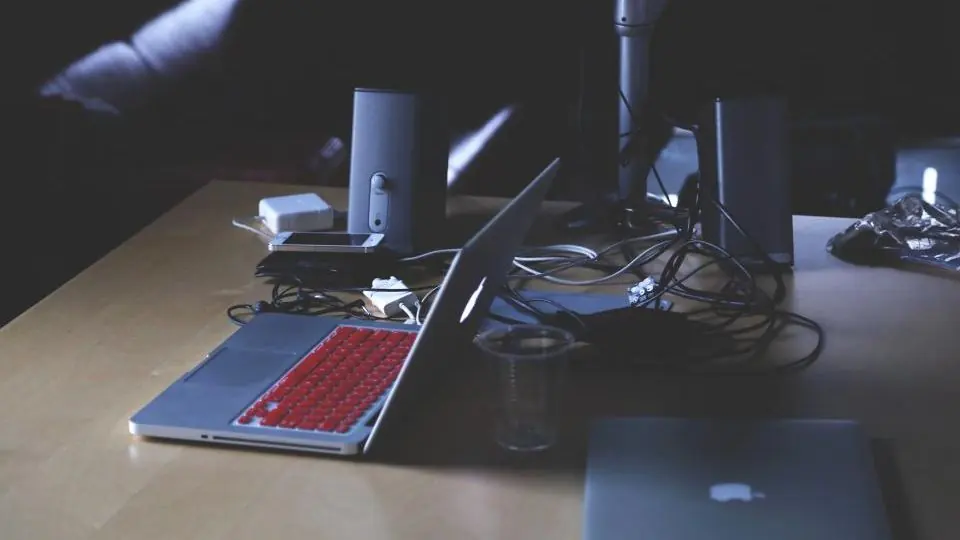 A laptop and cables on a dark desk